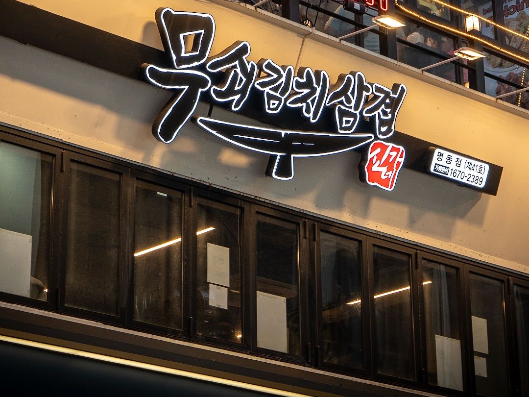 야간에 불을 밝힌 무쇠김치삼겹 명동점 네온 간판과 2층 매장 건물 외관